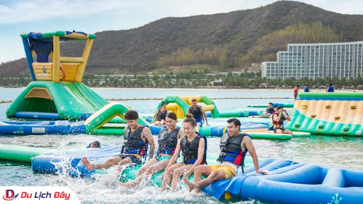Nhóm bạn trẻ mặc áo phao trải nghiệm các chướng ngại vật trên vịnh phao nổi khổng lồ ngoài bãi biển