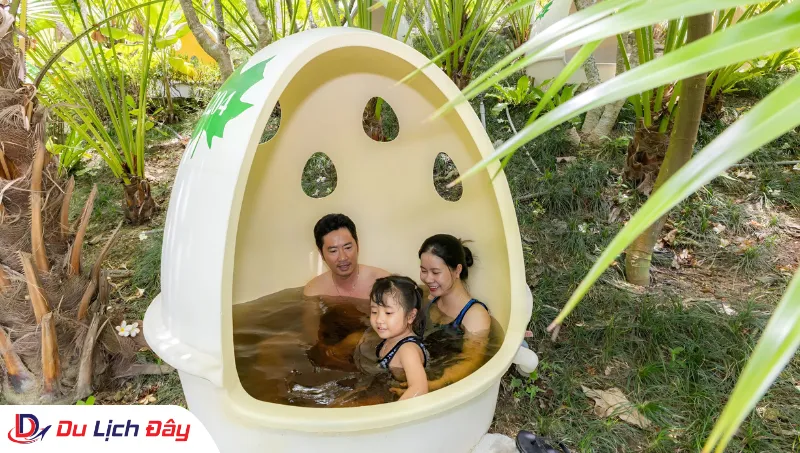 Gia đình du khách vui vẻ trải nghiệm tắm khoáng bùn tại KDL Trăm Trứng trong Tour Buôn Ma Thuột - Nha Trang 2N1Đ