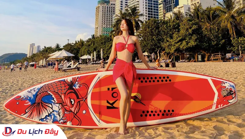 Du khách tạo dáng bên SUP tại biển Hòn Chồng trong Tour Chèo SUP City